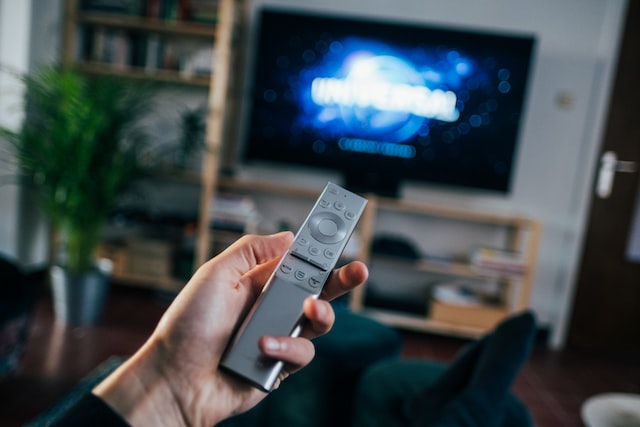 Pessoa segura controle de tv que está ligada em filme